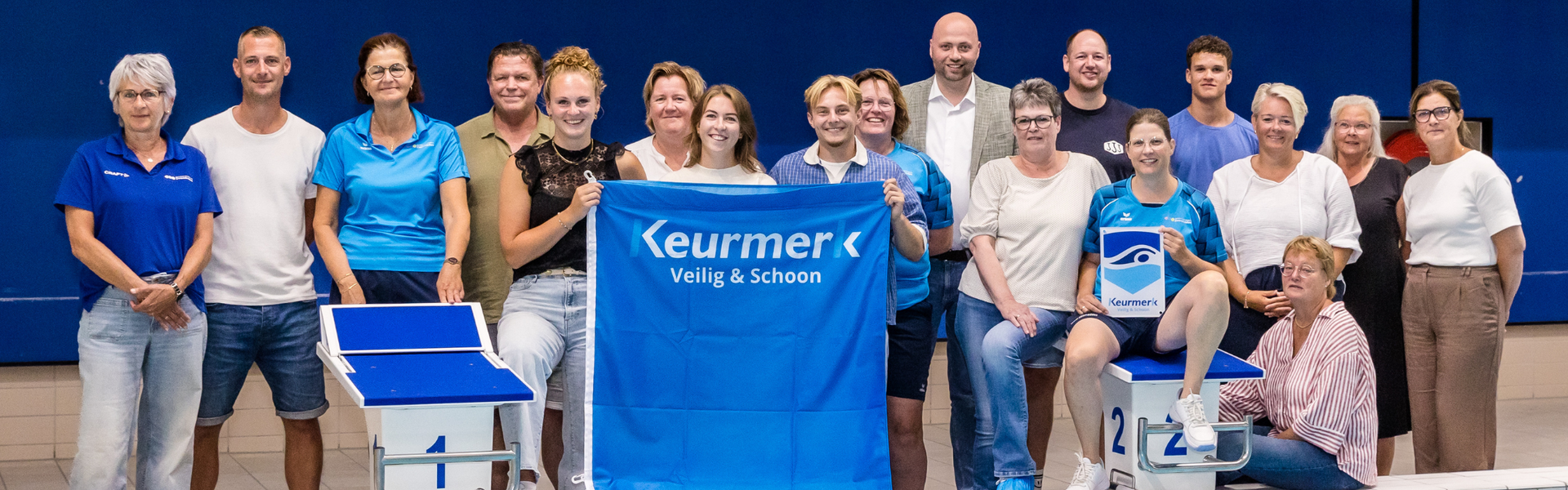 Foto van zwembadpersoneel met wethouder Piet-Cees van der Wel die een vlag met het keurmerk omhoog houden