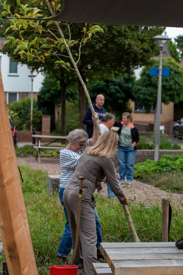 Elma Soeten plant een boom op het plein met een bewoner